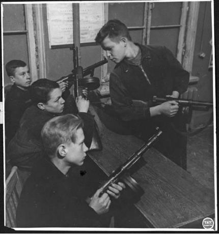 Обложка книги Ко второй годовщине Всевобуча. Красногвардейский ВУП вышел на первое место среди городских ВУПов. Командир взвода автоматчиков П. П. Иванов объясняет бойцам устройство пистолета-пулемета. 16 сентября 1943 г. фотография