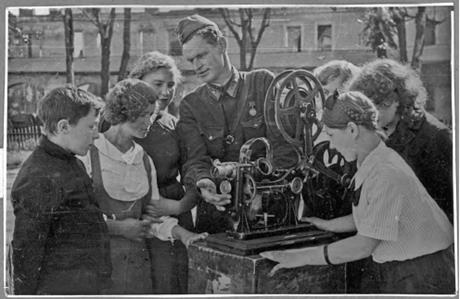 Обложка книги При кинотеатре "Комсомолец" в городе Тихвине идет подготовка киномехаников для работы на кинопередвижках в районах Ленинградской области, освобожденных от немецких оккупантов. Воентехник А. С. Черняк проводит занятие. 1 сентября 1942 г. фотография